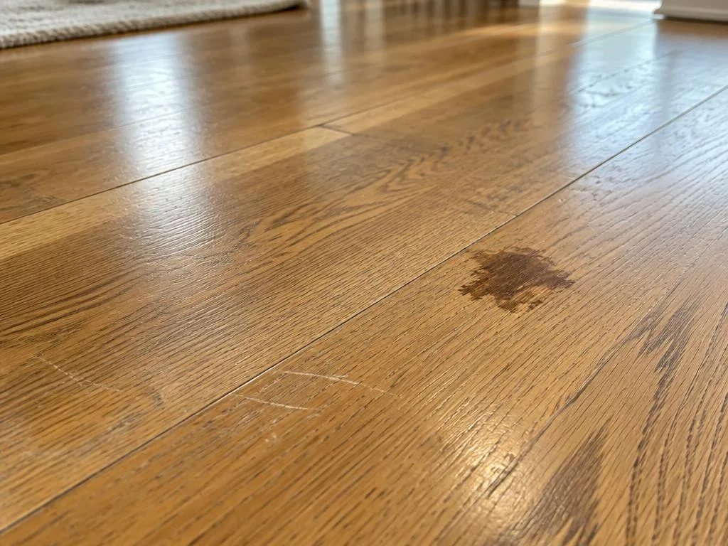 Worn oak hardwood floor showing scratches, faded finish and localized staining.